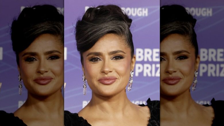 Salma Hayek dans une robe noire et un chignon élégant avec ses cheveux gris visibles