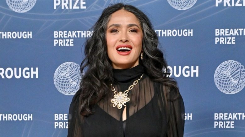Salma Hayek posant dans un haut noir transparent avec ses gris visibles