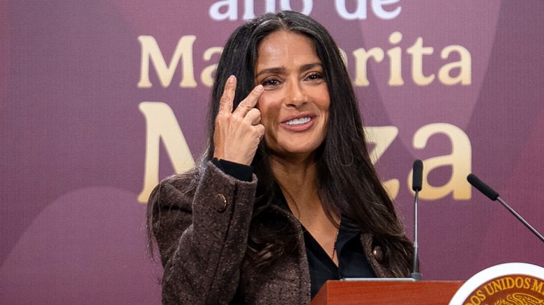 Salma Hayek s'exprimant sur un podium avec ses cheveux gris visibles
