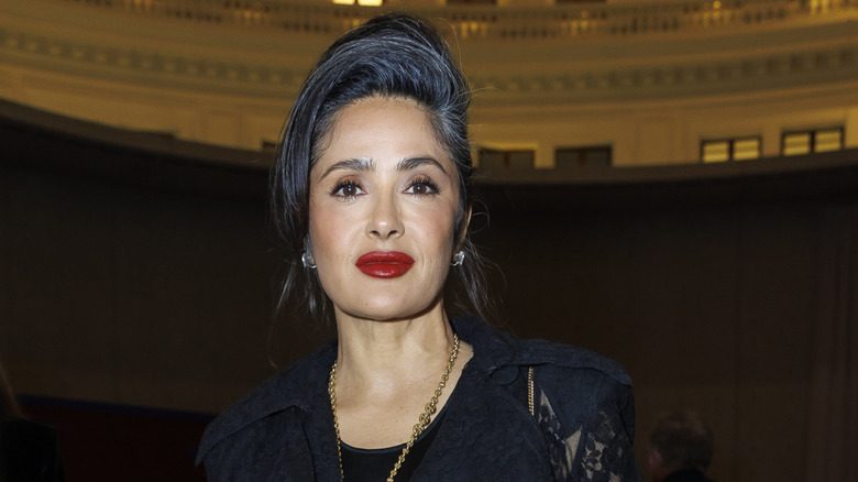Salma Hayek dans une robe noire et un chignon élégant avec ses cheveux gris visibles