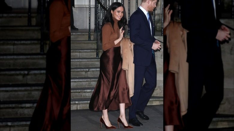 Meghan Markle porte une tenue marron monochrome avec les cheveux détachés.