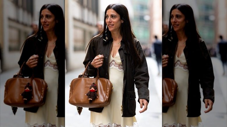 Une femme marche dans la rue à Paris avec un sac en cuir
