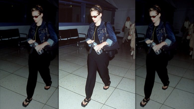 Winona Ryder photographiée à l'aéroport avec un pantalon noir, une veste en jean et des lunettes de soleil.
