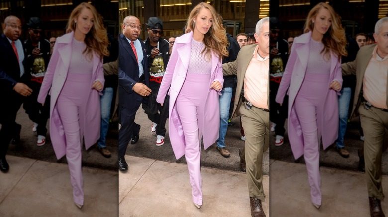 Blake Lively marchant dans une coupe rose composée d'un pantalon taille haute, d'un haut en résille et d'un manteau assorti