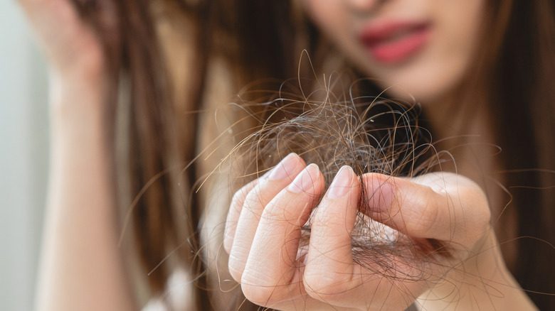 Femme tenant les cheveux tombés à la main