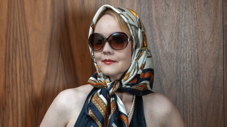 une femme âgée élégante accessoirisant avec un foulard en soie