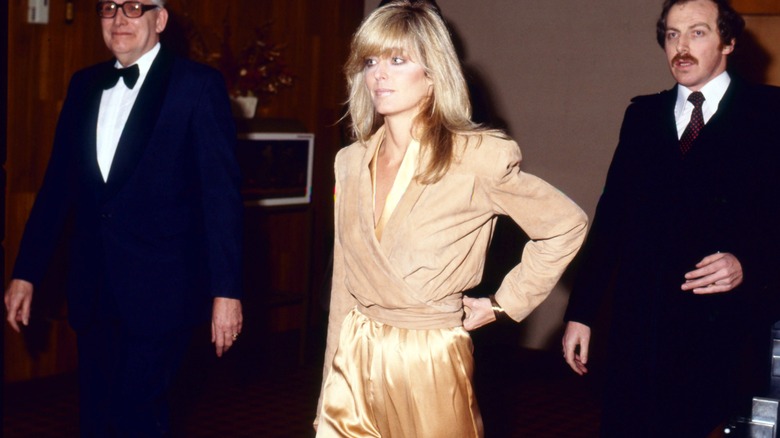 Farrah Fawcett porte une veste beige et une combinaison dorée