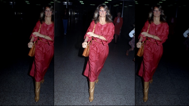 Farrah Fawcett porte une robe rouge et des bottes marron