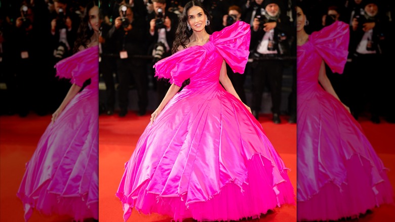 Demi Moore posant pour une photo dans une robe rose vif avec un gros nœud de Matières Fécales au Festival de Cannes 2026