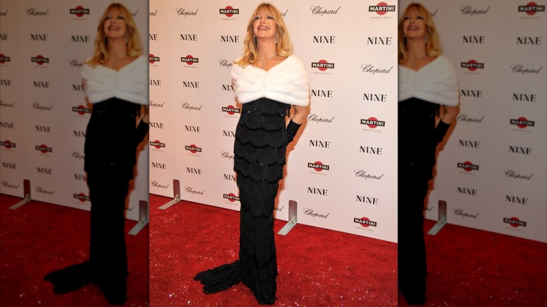 Goldie Hawn posant lors d'un événement sur le tapis rouge en 2009, vêtue d'une robe de soirée noire avec une étole en fourrure blanche.