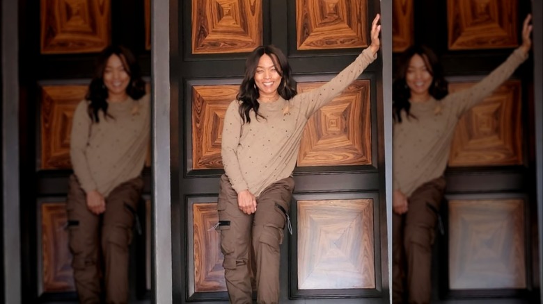 Angela Bassett posant dans une tenue marron avec la main sur le mur.