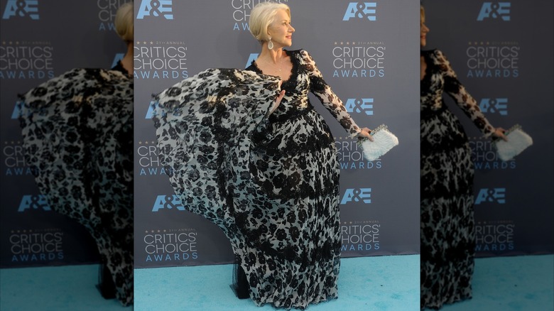 Helen Mirren posant lors d'un événement sur le tapis rouge en 2016, vêtue d'une robe fluide noire et blanche.