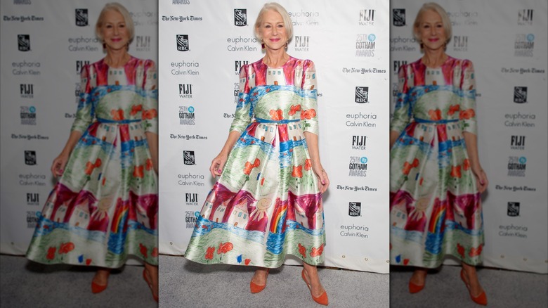 Helen Mirren posant lors d'un événement en 2015, vêtue d'une robe colorée avec des chaussures orange.