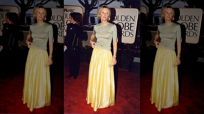 Meg Ryan posant sur le tapis rouge vêtue d'une jupe en satin jaune.