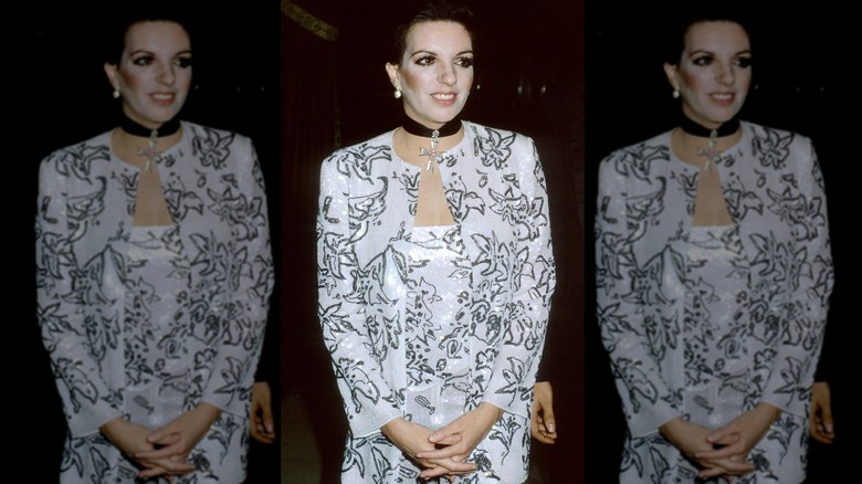 Liza Minnelli posant les mains jointes, vêtue d'une tenue blanche et noire et d'un collier ras du cou noir.