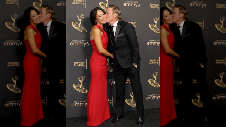 Chip Gaines portant un costume et embrassant sa femme Joanna Gaines portant une robe rouge lors d'un événement sur le tapis rouge.