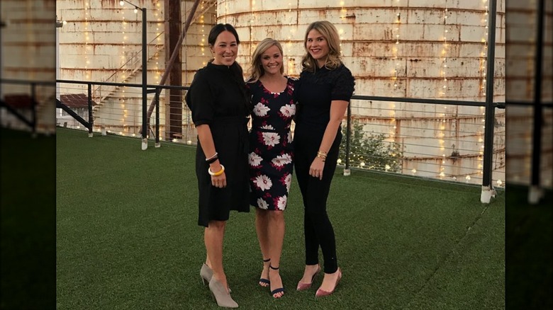 Joanna Gaines vêtue de noir souriante à côté de Reese Witherspoon dans une robe à fleurs et Jenna Bush Hager tout en noir.