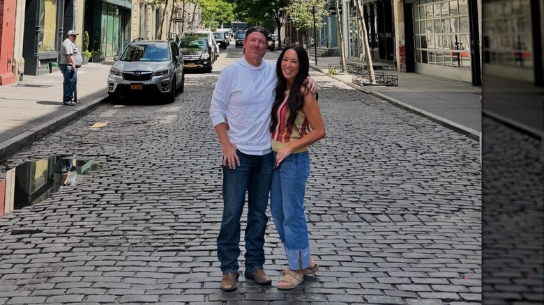 Chip Gaines en jean et t-shirt et Joanna Gaines en débardeur et jean posent les bras l'un autour de l'autre.