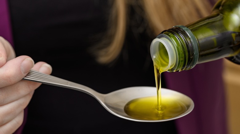 Image rapprochée de l'huile d'olive mesurée dans une cuillère à soupe.