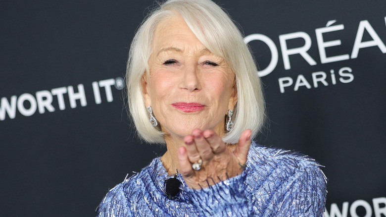 Helen Mirren porte une robe bleue et envoie un baiser sur le tapis rouge.