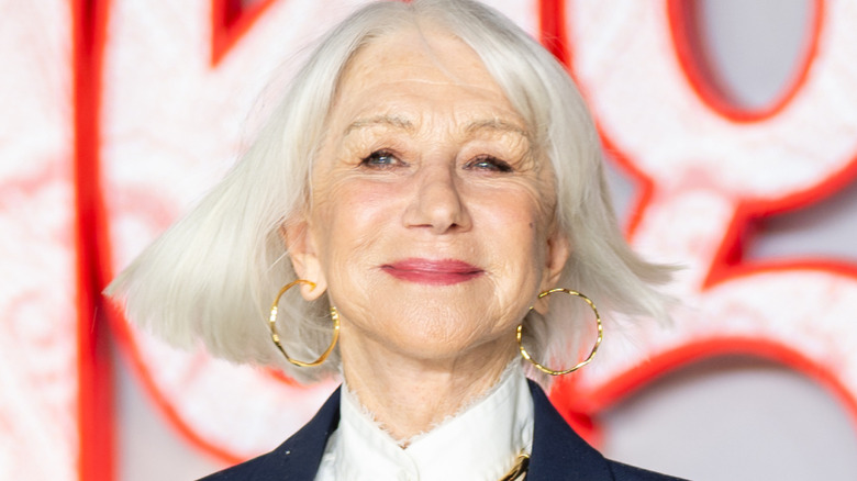 Helen Mirren posant sur le tapis rouge avec des boucles d'oreilles en or.
