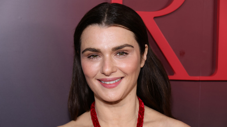 Rachel Weisz avec des cheveux lisses en arrière et une robe rouge