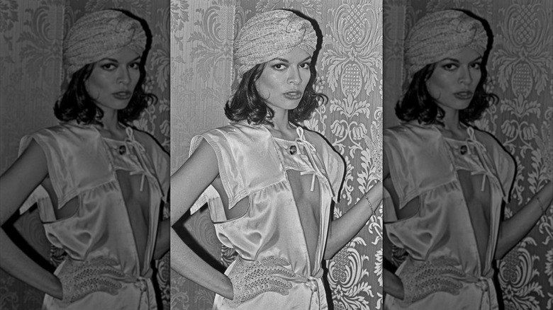 Bianca Jagger posant dans une séance photo en noir et blanc portant un chapeau turban et une tenue éclectique.