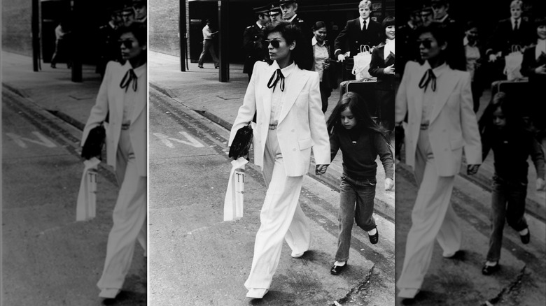 Bianca Jagger portant un costume blanc croisé tenant la main de sa fille Jade.