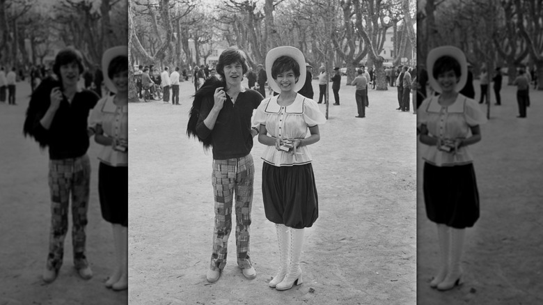 Mick Jagger portant un pantalon madras et un polo posant avec sa femme Bianca Jagger vêtue d'une tenue d'antan.