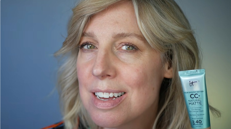 Image en gros plan d'une femme tenant un tube de crème IT Cosmetics CC.