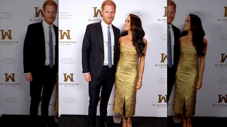 Meghan Markle portant une robe dorée pose aux côtés du prince Harry sur le tapis rouge des Ms. Foundation Women of Vision Awards