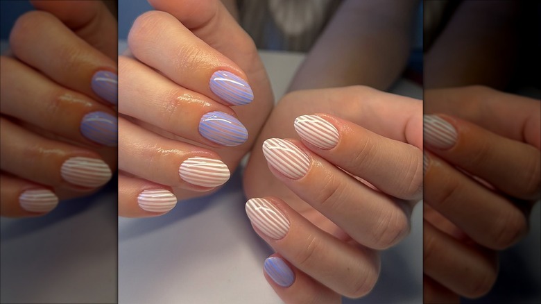 Ongles courts avec de fines rayures bleues et blanches.
