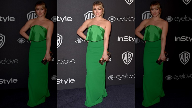 Hilary Duff posant lors d'un événement avec la main sur la hanche, vêtue d'une robe bustier vert émeraude.