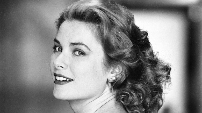 Photo en noir et blanc de Grace Kelly, les cheveux détachés et le visage légèrement tourné vers la caméra, souriant.