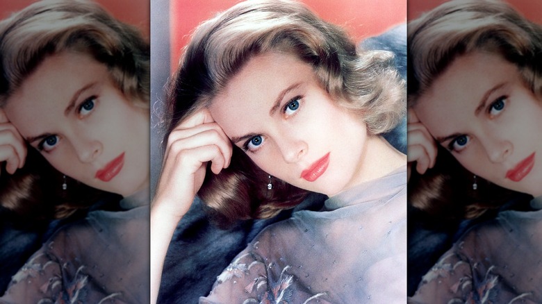 Grace Kelly posant avec la tête sur la main, portant un haut gris, un maquillage simple et des cheveux doux.