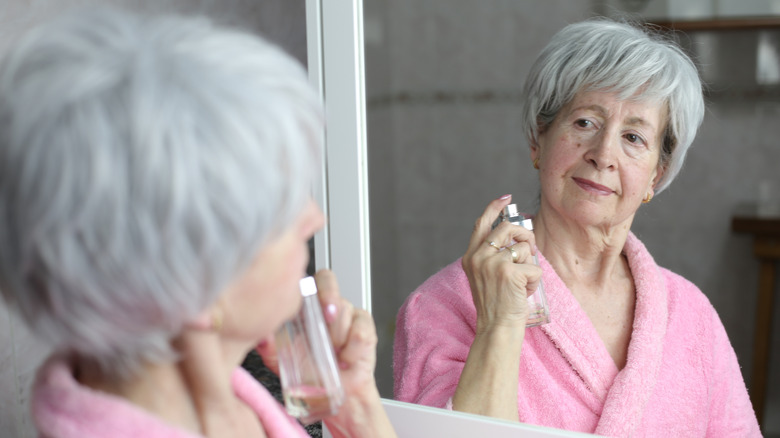 Femme âgée utilisant du parfum dans la salle de bain