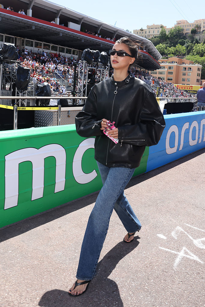 Kika Cerqueira Gomes avec un look jean, veste en cuir et sandales noires.