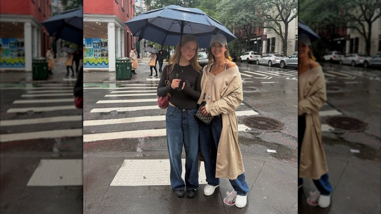 Jessica Alba posant dehors sous la pluie avec sa fille Haven tenant un parapluie.