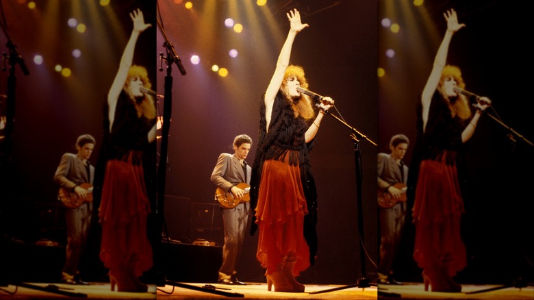 Stevie Nicks sur scène avec la main en l'air, vêtue d'une jupe rouge et d'un haut noir, jouant avec Fleetwood Mac en 1979.