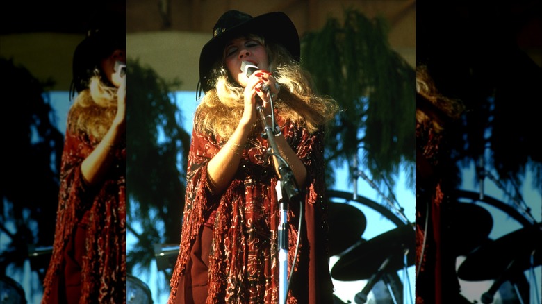 Stevie Nicks portant un chapeau noir et une tenue rouge jouant avec Fleetwood Mac en 1977.