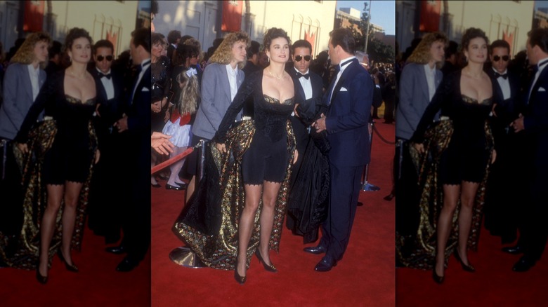 Bruce Willis en smoking et Demi Moore portant une tenue bleue et noire avec une cape sur le tapis rouge des Oscars.