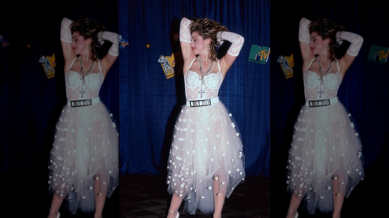 Madonna, les mains levées, portant une tenue en dentelle blanche, des gants en dentelle blanche et une ceinture Boy Toy aux MTV Video Music Awards.