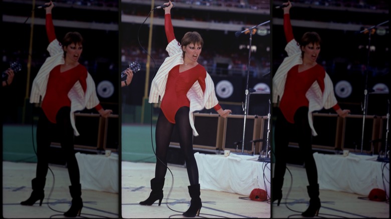 Pat Benatar portant un body rouge avec des leggings et des bottes noirs se produisant sur scène.