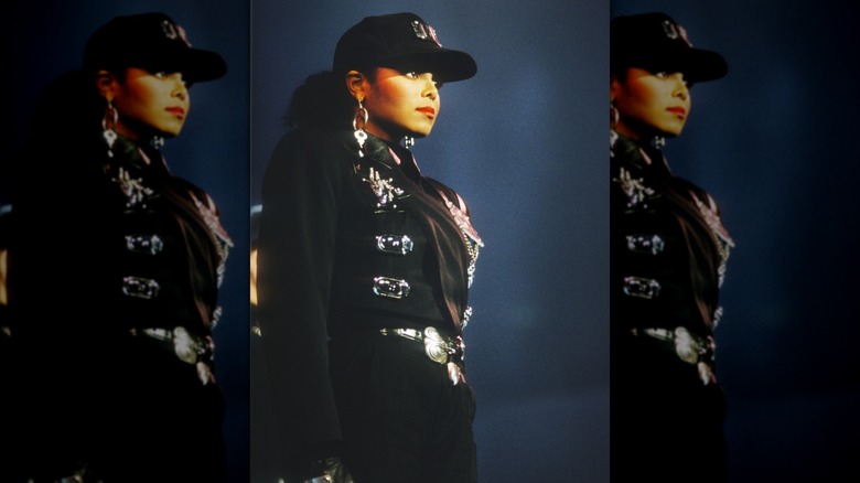 Janet Jackson posant sur scène avec une casquette noire et une tenue noire d'inspiration militaire lors de sa tournée Rhythm Nation.