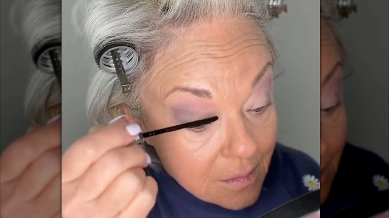Femme mûre appliquant le mascara