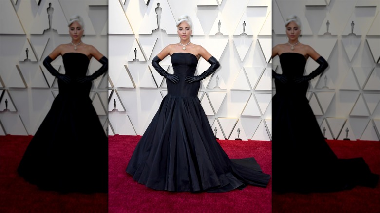 Lady Gaga pose les mains sur les hanches et porte des gants noirs