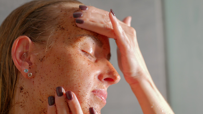 Une femme utilisant un exfoliant physique sur son visage, ce qui pourrait être trop agressif pour les femmes dans la quarantaine.