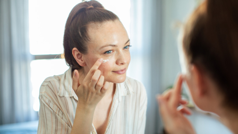 Une femme appliquant une crème hydratante sur son visage