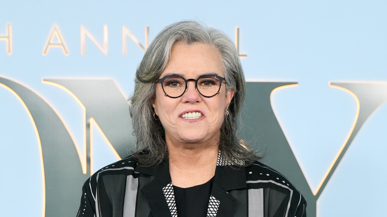 Rosie O'Donnell souriante et portant une veste noire et des lunettes