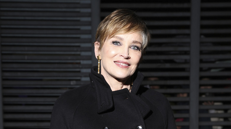 Sharon Stone porte une coupe lutin rayée de gris et un caban noir lors de la mode milanaise 2024